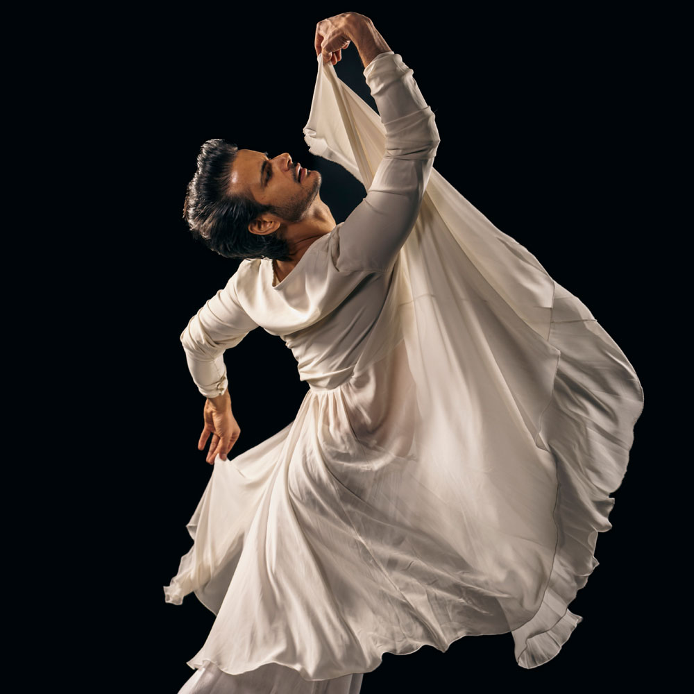 Dancer in rehearsal, ivory costume against a dark background